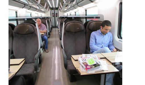 Photo shows a train with large, roomy seats, and only two passengers.